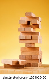 The Concept Of Entrepreneurial Risk With The Jenga Model. Wooden Blocks On A Yellow Background