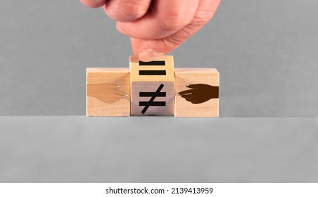 Concept Of Equality Drawn On Wooden Cubes. A Hand Changes An Unequal Sign To An Equal Sign Between A White And A Dark Hand.