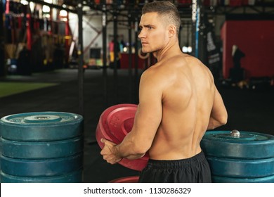 Concept Of Etiquette In The Gym - Rack The Weights After Your Workout. Muscular Bodybuilder Is Holding Plate From Barbell