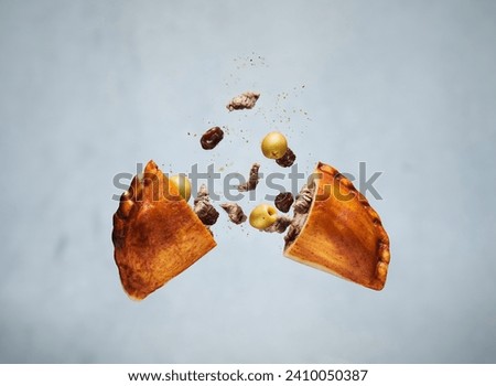 Concept of an exploded Argentine empanada with beef, olives, raisins, and spices; food art levitation