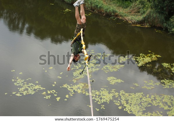 Concept of Extreme Sports and Fun. A man is a 
thrill-seeker and a  rope jumper from the bridge. He is very happy
to make a dream come true. He  is holding an action camera and
insanely happy