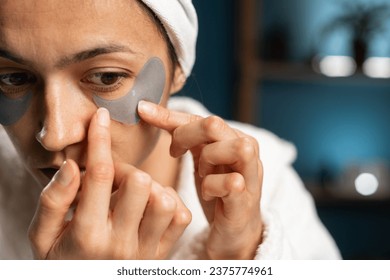 Concept of face skin care. Attractive woman applying under eyes patch on face and watch in mirror. Close-up - Powered by Shutterstock