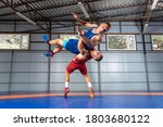 The concept of fair wrestling. Two greco-roman  wrestlers in red and blue uniform making a suplex wrestling  on a wrestling carpet in the gym.The concept of male wrestling and resistance