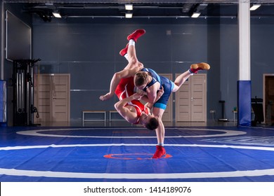 The concept of fair wrestling. Two greco-roman  wrestlers in red and blue uniform wrestling   on a wrestling carpet in the gym.The concept of fair wrestling