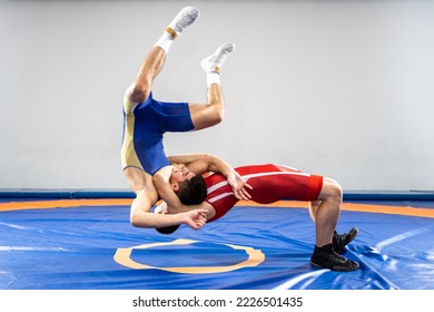 The concept of fair wrestling. Two greco-roman  wrestlers in red and blue uniform wrestling   on a wrestling carpet in the gym.The concept of fair wrestling - Shutterstock ID 2226501435