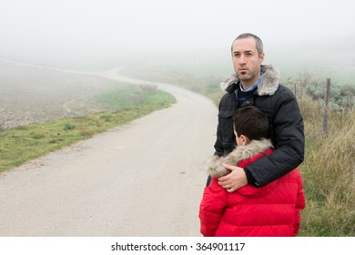 Concept of family escaping.  Father and son in a mountain road with fog. Scene with actors - Shutterstock ID 364901117