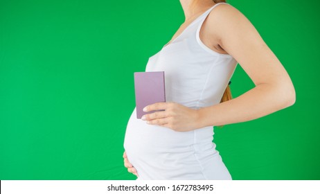 Concept Of A Family And Expectation As A Pregnant Woman Is Holding A Travel Document, Passport Next To Her Belly Expecting A New Chapter Of Her Life With The New Baby