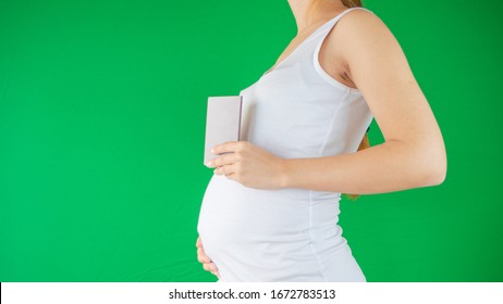 Concept Of A Family And Expectation As A Pregnant Woman Is Holding A Travel Document, Passport Next To Her Belly Expecting A New Chapter Of Her Life With The New Baby