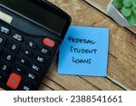 Concept of Federal Student Loans write on sticky notes isolated on Wooden Table.