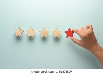 The Concept Of Feedback Of Five Stars. The Hand Adds A Red Star To The Four Ordinary Ones.