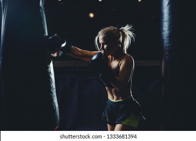 Concept female sport. Strong athletic young blond woman is training self-defense punches in boxing gloves. - Powered by Shutterstock