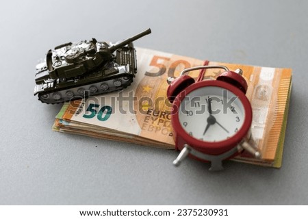 The concept of financing war and armaments. toy tank, euro, clock