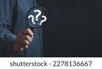 The concept of finding an answer to complex questions in business. Hand holding a magnifying glass with question mark.