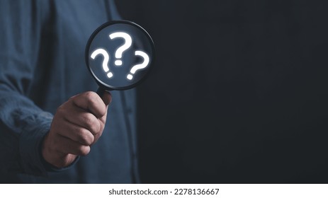 The concept of finding an answer to complex questions in business. Hand holding a magnifying glass with question mark. - Shutterstock ID 2278136667