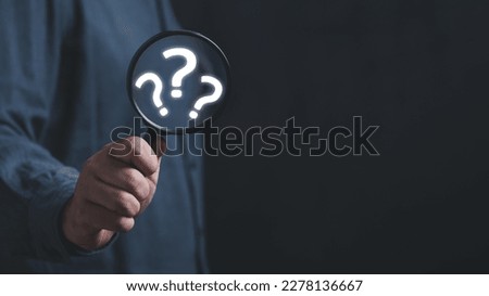 The concept of finding an answer to complex questions in business. Hand holding a magnifying glass with question mark.