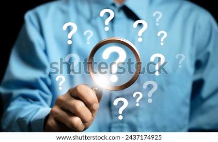 The concept of finding an answer to complex questions in business. Hand holding a magnifying glass with question mark.