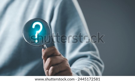The concept of finding an answer to complex questions in business. Hand holding a magnifying glass with question mark.	
