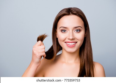 Concept Of Finding A Good Solution In Treating Damaged Hair Ends. Pretty Cute Smiling Woman Is Showing Her Healthy Hair, Isolated On Grey Background