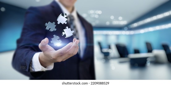 The concept of finding solutions to complex problems in business. Businessman shows jigsaw puzzles on office background. - Shutterstock ID 2209088529