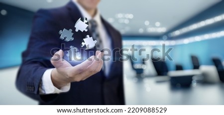 The concept of finding solutions to complex problems in business. Businessman shows jigsaw puzzles on office background.