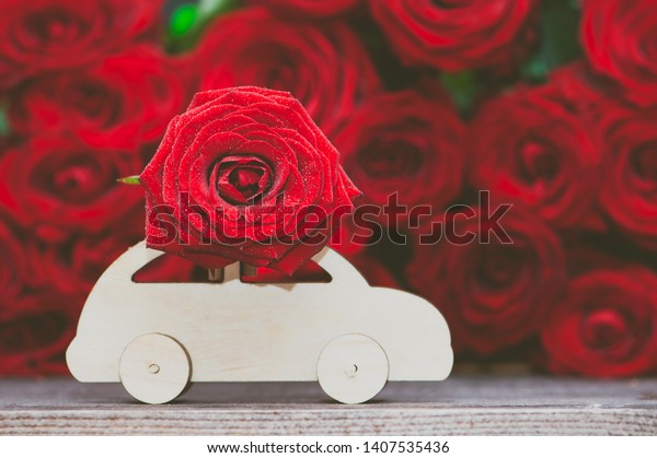 Concept of flower delivery,\
love, typewriter transports a flower against a background of red\
roses.