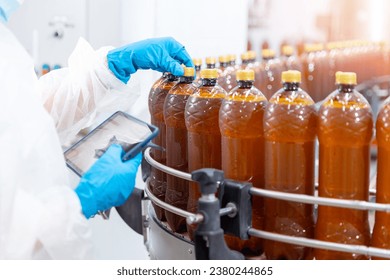 Concept food industry banner. Factory worker inspecting production line with brown plastic beer bottles on Brewery plant with computer tablet. - Powered by Shutterstock