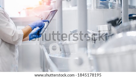 Concept food industry banner. Factory worker inspecting production line tanker in of dairy factory with computer tablet.