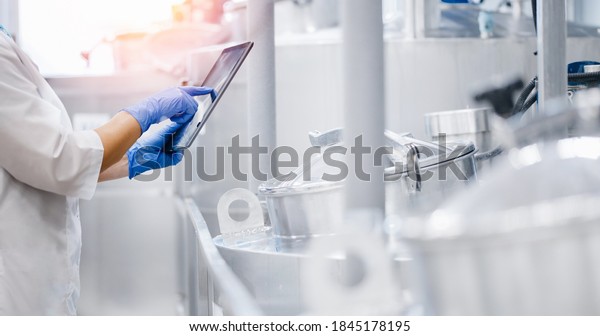 Concept\
food industry banner. Factory worker inspecting production line\
tanker in of dairy factory with computer\
tablet.