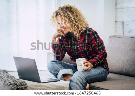 Concept of free and hapy people work with computer technology at home not office - cheerful caucasian woman with laptop sit down on the sofa with window in background