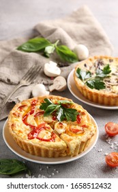 The concept of French cuisine. Quiche with peppers, tomatoes and mushrooms on a light background. Background image, copy space