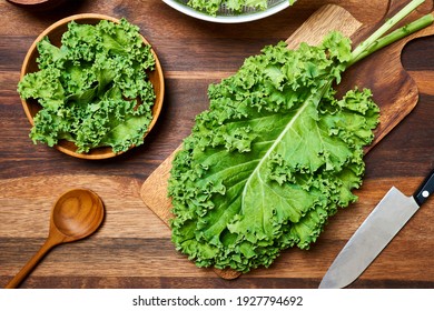 concept of fresh kale leaves salad on wooden table background. preparing green kale leaves salad food in the kitchen. flat lay, top view                               