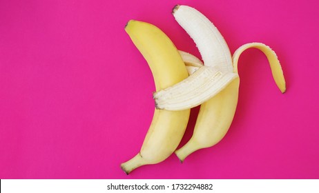 The Concept Of A Friendly Couple. Banana Like A Husband Embraces Another One Like A Wife. Gay Couple Idea. Solid Pink Background.