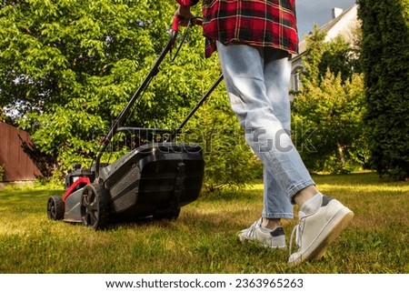 Concept of gardening, work, nature. Housework, gardening and country life. Home garden grass cutting woman mowing with lawn mower. Detail of lawn mower. Сutting grass in backyard. Sunny autumn day. Stockfoto © 