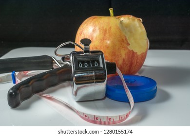 Concept - Getting in Shape. Closeup on Measuring Tape, Click counter and Apple