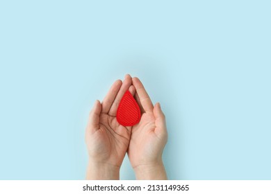 Concept Of Give Blood Donation, Blood Transfusion. Hands Woman Hold Drop Of Blood On Blue Background. World Hemophilia Day. World AIDS And Hiv Day. Copyspace. Top View Banner