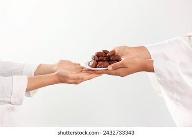 Concept Giving or Charity during Ramadhan Holy Month, Female Muslim Hand Over A Plate of Dates Fruit Kurma to Other. Ifthar and Ramadan Kareem Concept. 