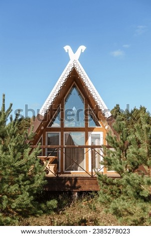 The concept of glamping and renting a chalet for weekend. Wooden house with a veranda in nature around coniferous trees.
