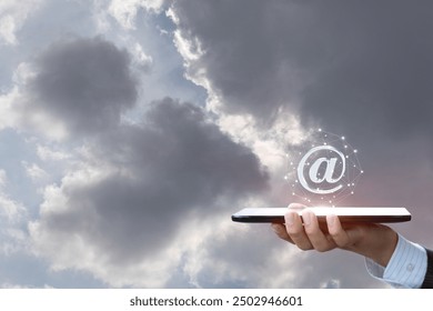 The concept of global interaction. Hand with tablet showing email icon against sky background. - Powered by Shutterstock - Get 15% off with code: PIKWIZARD15