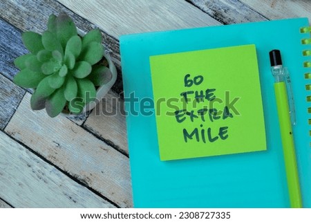 Concept of Go The Extra Mile write on sticky notes isolated on Wooden Table.