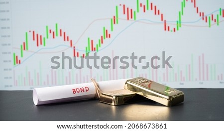 Concept of gold bond showing with Gold bars and Bod paper with Stock Market Graphs or charts in background