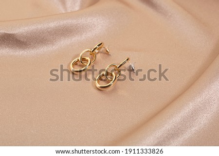 
Concept gold earrings on a brown fabric background.