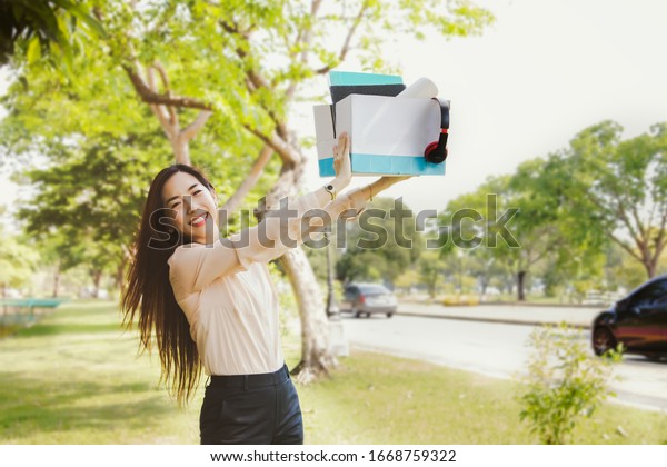 Concept Good start in\
the morning : Positive business women to start working on a new\
day, picking up a document box to prepare for work in a good mood\
amidst green nature.