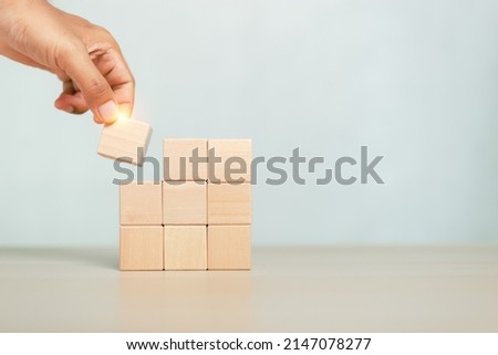 concept of grow success. hand holding and stacking wooden block cube step of business growth success.