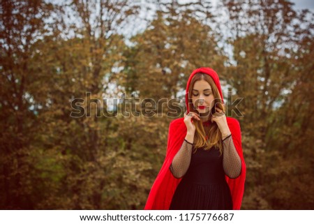  Concept of Halloween. Beautiful and simple costume of little red hood. Mysterious hooded lady figure . Girl in red raincoat. Cosplay Fairy Tale Little Red Riding Hood