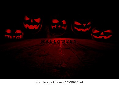 The Concept Of Halloween. Many Evil Scary Pumpkins Flying In The Dark With A Blue Ice Glow. Jack Lantern In The Middle Of The Darkness With An Inscription Of Halloween And Smoke