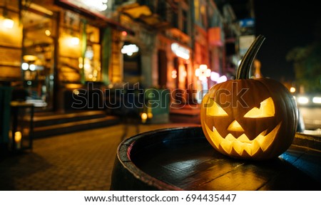 The concept of Halloween. Pumpkin with a face stands on the street and decorates the street scaring passers-by people.