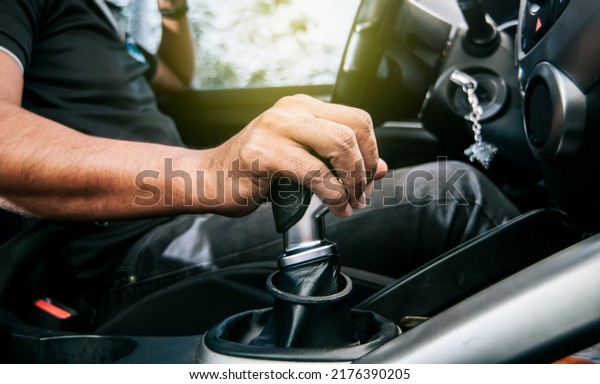 Concept of hand grabbing\
the gear lever of a car with copy space, Close-up of driver hand on\
the gear lever of a car, close-up of hands accelerating on the gear\
lever