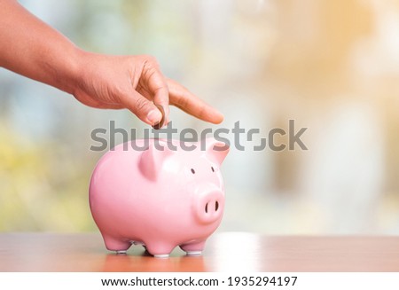 Concept hand putting money coin into piggy bank saving money for future plan and retirement fund, Business or finance saving show putting coin saving and investment money  retro vintage color tone.