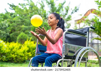 concept of happiness, freedom and enjoyment showing by Smiling alone girl kid with disability playing with ball while on wheelchair at park. - Powered by Shutterstock