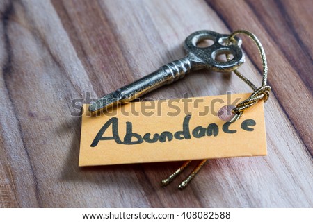 concept for a happy abundant life using an old decorative key and a hand written tag attached by a golden cord